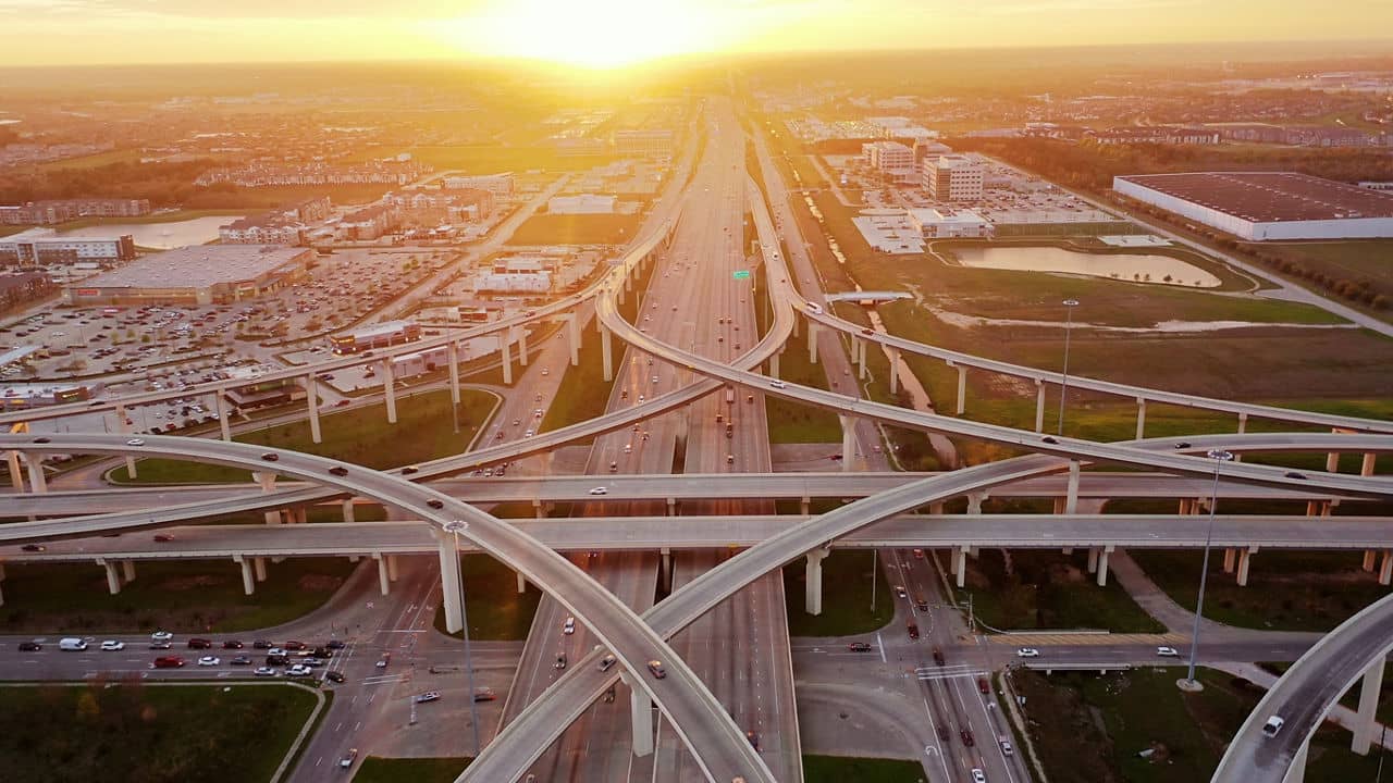 Aerial view of highways and roads in Katy, Texas, during sunset with buildings and greenery in the background.